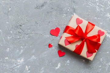 Top view photo of valentine day decorations gift box with red ribbon bow on colored background....