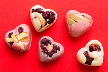 chocolate sweets in the form of a heart with fruits and nuts on a colored background. top view with space for text, holiday concept