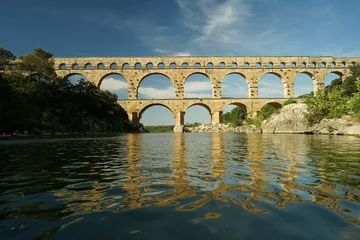 Papier Peint photo autocollant Pont du Gard Pont du Gard famous aqueduct arched bridge mirroring in Gardon river, popular tourist landmark in France