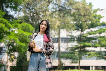 A confident young Asian female college student is looking at the camera while standing in the park.