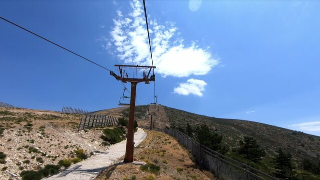 Scenic chairlift ride to the top of the mountain without snow out of season in Puerto de Navacerrada in the Sierra de Guadarrama, Madrid, Spain. Point Of View (POV), subjective view