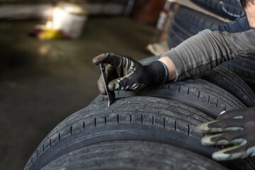 Mechanic assessing tire with calipers