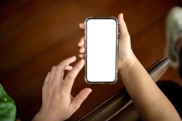 A woman holding a white-screen smartphone mockup over a blurred rustic wood background.