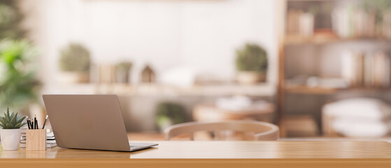 A back view image of a laptop computer on a wooden table in a cozy neutral room.