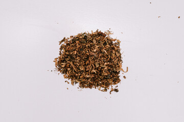 Brown colored cigarette tobacco with a slightly wet texture is ready to be made into several cigarettes for mixing.