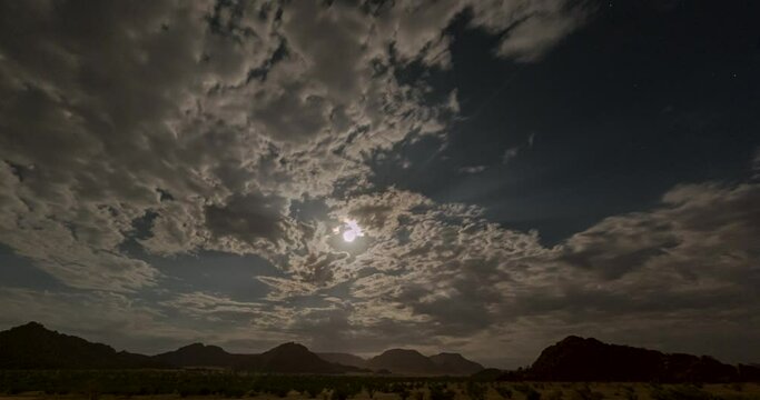 Day to night time lapse movie of the night sky over Namibia with fast moving clouds in front of the full moon