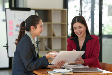 Business team Negotiation, Analysis, Discussion, Asian woman economist and marketer pointing to a financial data sheet to plan investments to prevent risks and losses for the company.