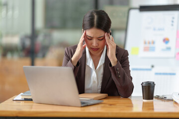 Asian businesswoman who is tired has a headache, is stressed, sleepy, angry, and bored from sitting...