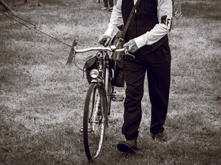 Second world war commemoration at SAINTE MERE L'EGLISE In Normandy, FRANCE. Vintage dressed man with cycle during 1940 years - obrazy, fototapety, plakaty