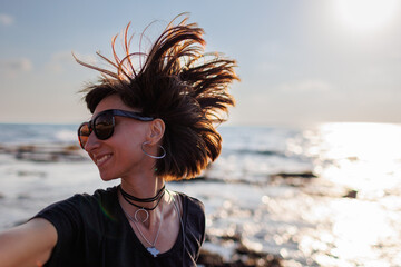 young girl with hair flying in the wind. Portrait of a stylish and cheerful girl posing on the beach. - 776950671
