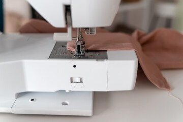 pattern, scissors, tape measure, and a sewing machine. Workplace of seamstress. Dressmaker cuts dress detail on the sketch lines.