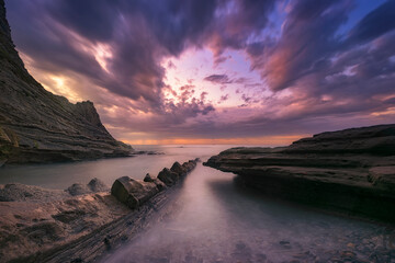 Tunelboka beach in Getxo, Bizkaia on a sunset with clouds and dramatic sky and with the sea beating...