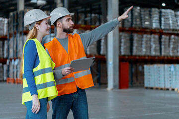 Workers, engineers, wearing protective workwear and helmets, using digital tablet, factory foreman