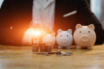 Businessmen holding light bulb In the office with stack of coins for creative concept..