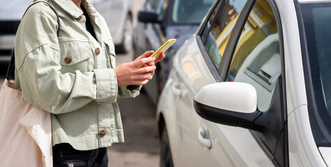 The woman unlocks the car rental vehicle using the mobile app. Woman with mobile phone connecting...