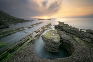 Tunelboka beach in Getxo at sunset with its flysch entering the sea calmed by a long exposure