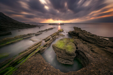 Tunelboka beach in Getxo at sunset with its flysch entering the sea calmed by a long exposure