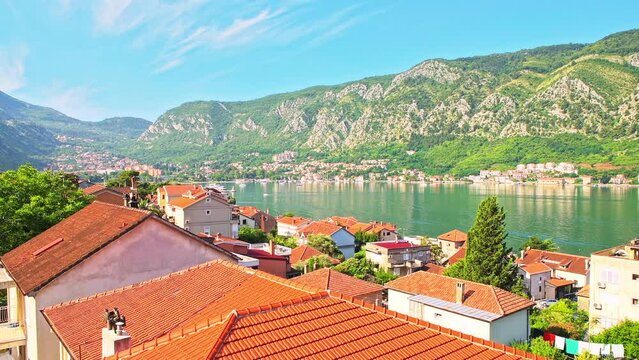 Kotor bay, Montenegro high angle aerial view on rooftop of red tile buildings roofs in summer, ships and cruise boats on water by mountains 