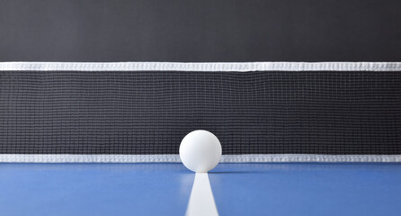 Ping-pong ball centered on blue table with black isolated background