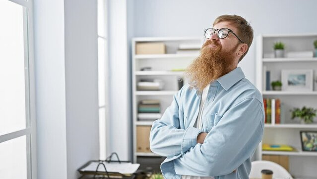 Confident redhead man smiling, arms crossed, feeling the success, standing relaxed in elegant office interior