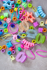 the 90’s are back. Nineties hair accessories, bright clips, beads, and hair ties on grey surface with copy space
