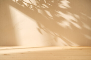 Empty table on stucco wall background with window shadow on the wall. Mock up for branding...