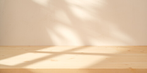 Empty wood table on neutral color background with natural shadows on the wall. Mock up for branding...