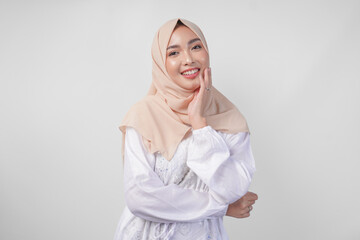 Portrait of beautiful Asian Muslim woman with natural make-up wearing white dress and hijab posing on white background in studio. Facial skin care, female beauty concept