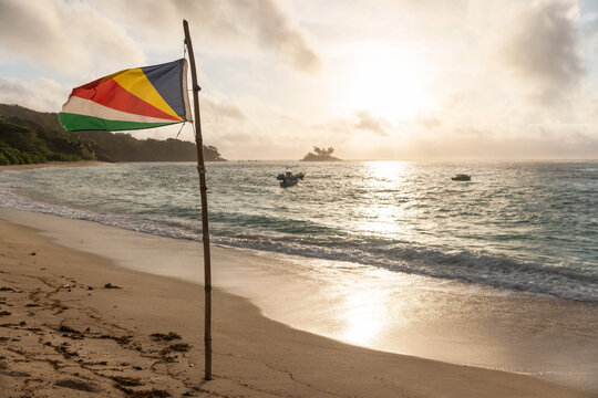 Flag of Seychelles stands on a sunset beach