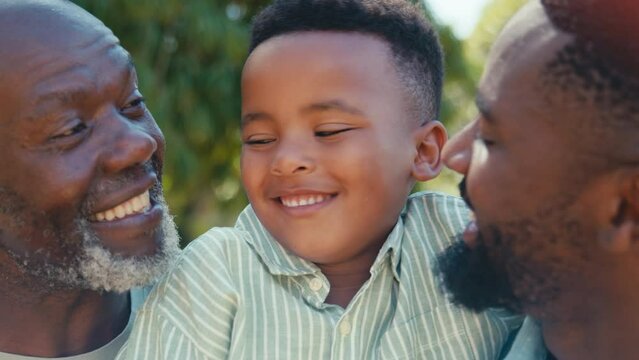 Close up of loving male three generation family laughing and hugging outdoors in summer countryside or garden - shot in slow motion