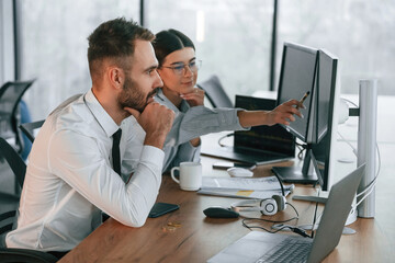 Analyzing information. Two employees are working in the office together