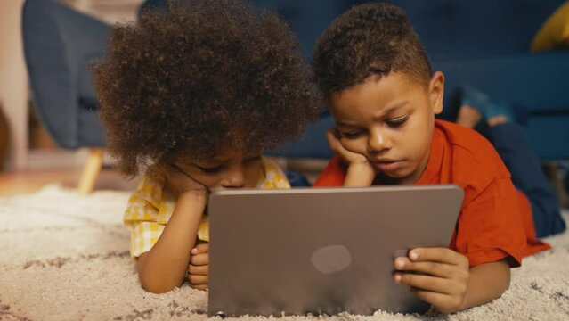 Adorable African American boys watching movie on tablet, modern app for kids