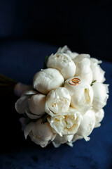 Bride's bouquet of white peonies with wedding rings