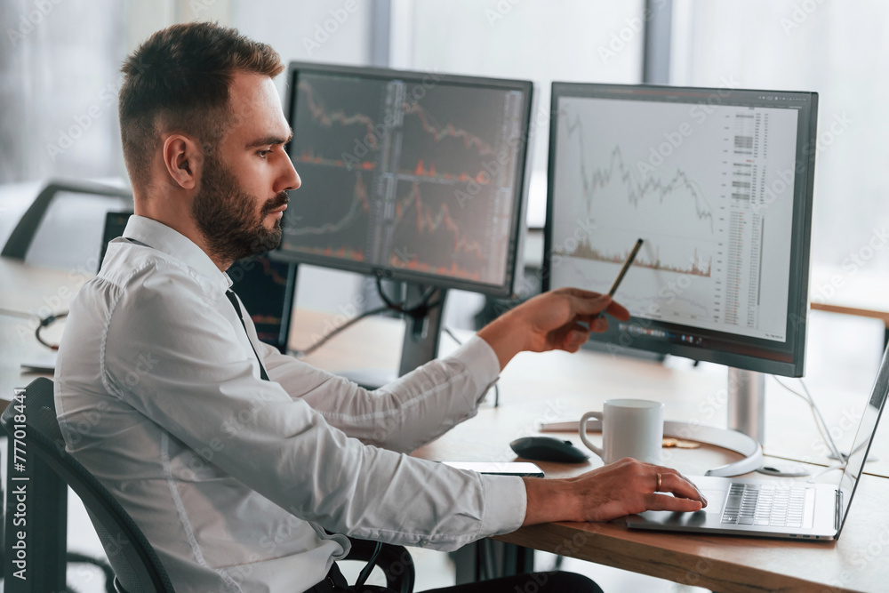 Poster using laptop. businessman is sitting by computer and working in the office