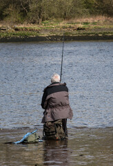 Older man fishing by a river