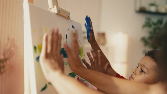 African American little boys and mom painting with their hands on canvas, art