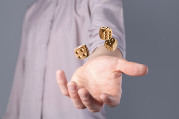 Man throwing golden dice on grey background, closeup