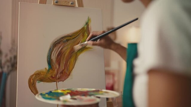 Professional woman artist painting a picture on easel stand, inspiration and art