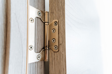 Closeup of hardwood door hinge on woodstained door