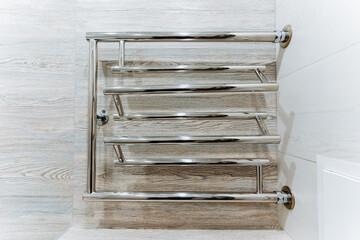 A metal towel rack with a rectangle handle sits on the bathroom floor