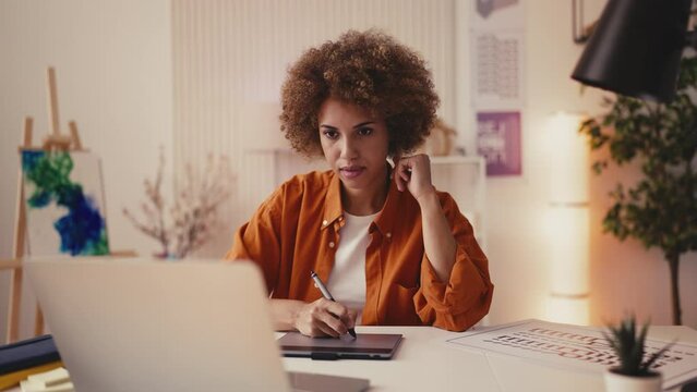 Happy African American designer working on graphic tablet, drawing sketches
