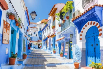 Papier Peint photo Lavable Ruelle étroite Photograph of the blue stairs in Chefchaouen, Morocco with pots on it, colorful houses and plants on a sunny day