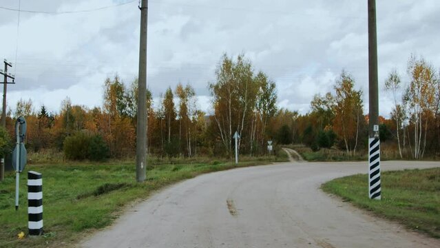 Passage through railway railroad crossing with multiple track crossbuck sign, crossing lights and electric bells. Rear windshield windscreen view, back glass screen. Autumn fall. Countryside road