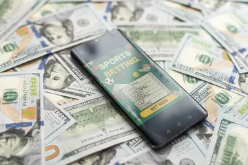 Foto op Plexiglas Smartphone with gambling mobile application with money close-up. Sport and betting concept © Angelov
