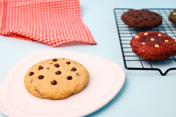 Tasty cookies with chocolate chips topping on white plate