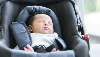 Portrait of adorable less than one month old newborn baby girl sleeping in the modern car seat with...