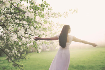 young woman dressed in white taking a breath in the middle of spring nature