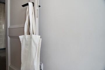 Eco friendly concept with white canvas tote bag hanging on door knob with two toned colored, Eco blank shopping sack with free copy space, Reduce plastic bags to reduce global warming. Canvas tote bag - obrazy, fototapety, plakaty