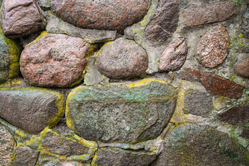 Old stone wall with moss and lichen. Rustic natural background.
