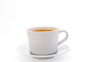 Creamy coffee on a white porcelain cup, isolated on white background with copy space. Side view, close-up.